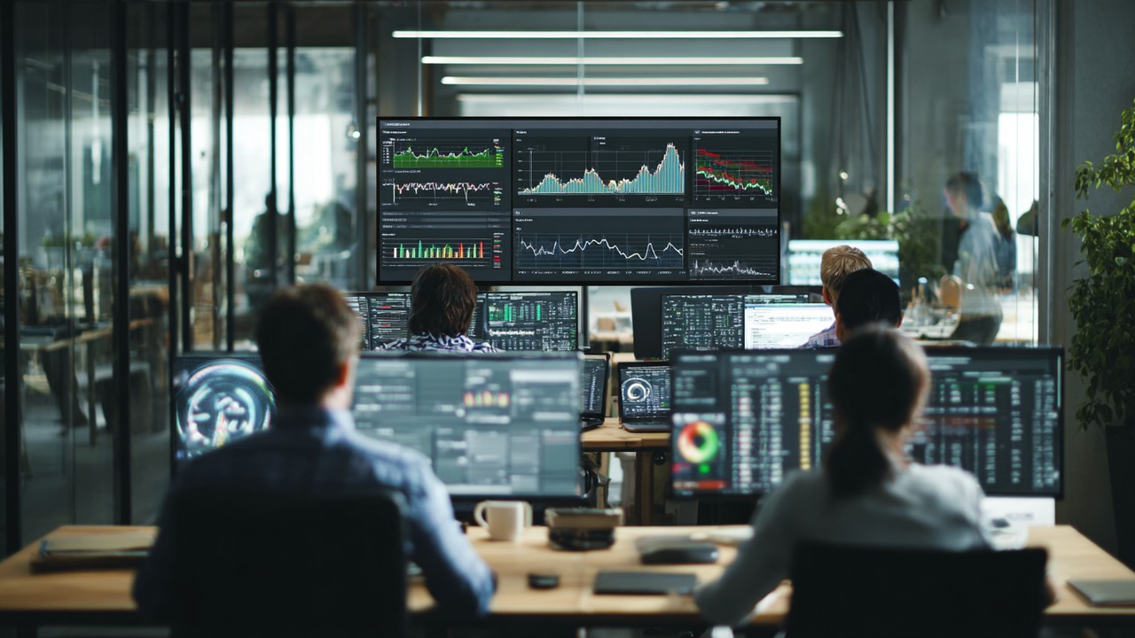Diverse professionals analyzing website performance data on multiple screens in a modern office, illustrating real user monitoring and data collection.