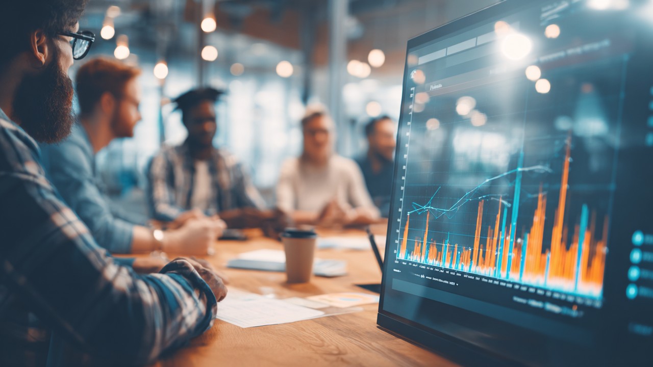 Diverse professionals in a business meeting analyzing website analytics and performance charts on a large screen.