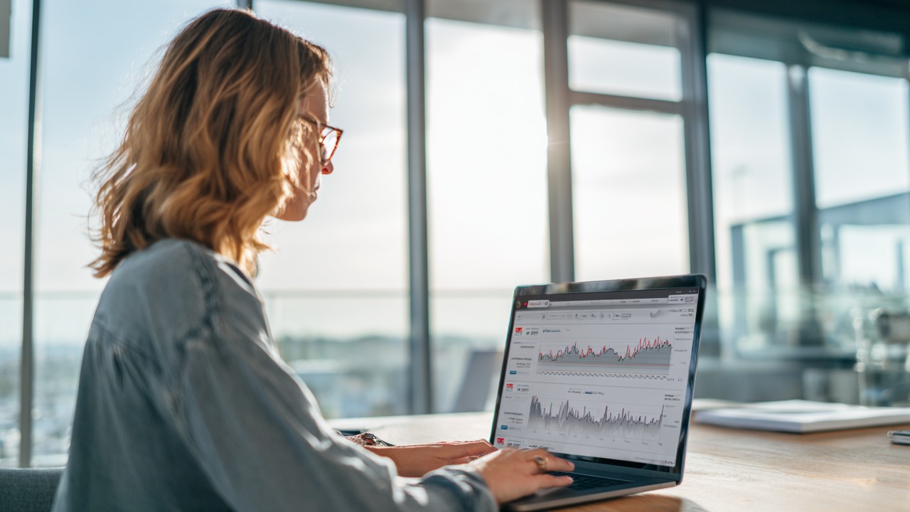 Focused professional working on a laptop with website analytics and loading speed graphs in a bright, modern office environment.