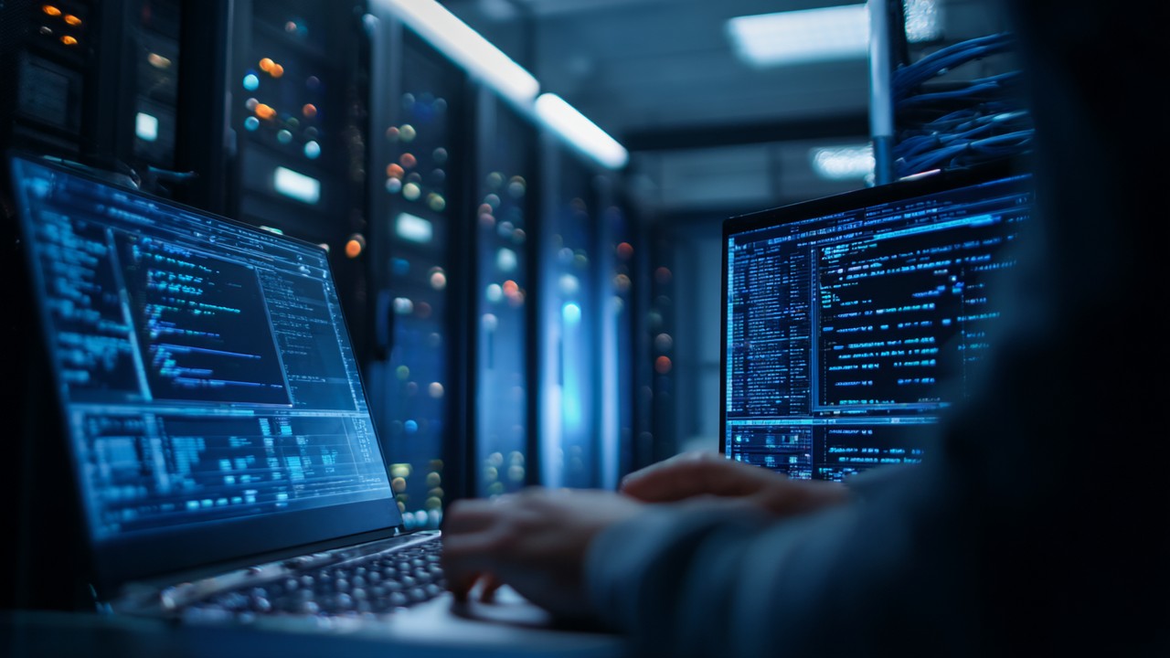 High-resolution image of a server room with glowing server racks and a developer working on a laptop displaying server configuration code, highlighting IT infrastructure and performance tuning.