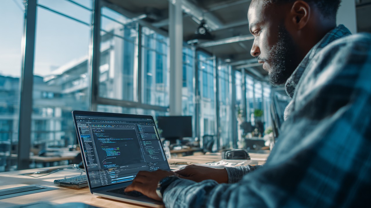 Professional web developer working on a laptop in a modern office, optimizing website performance with code editors and browser windows open.