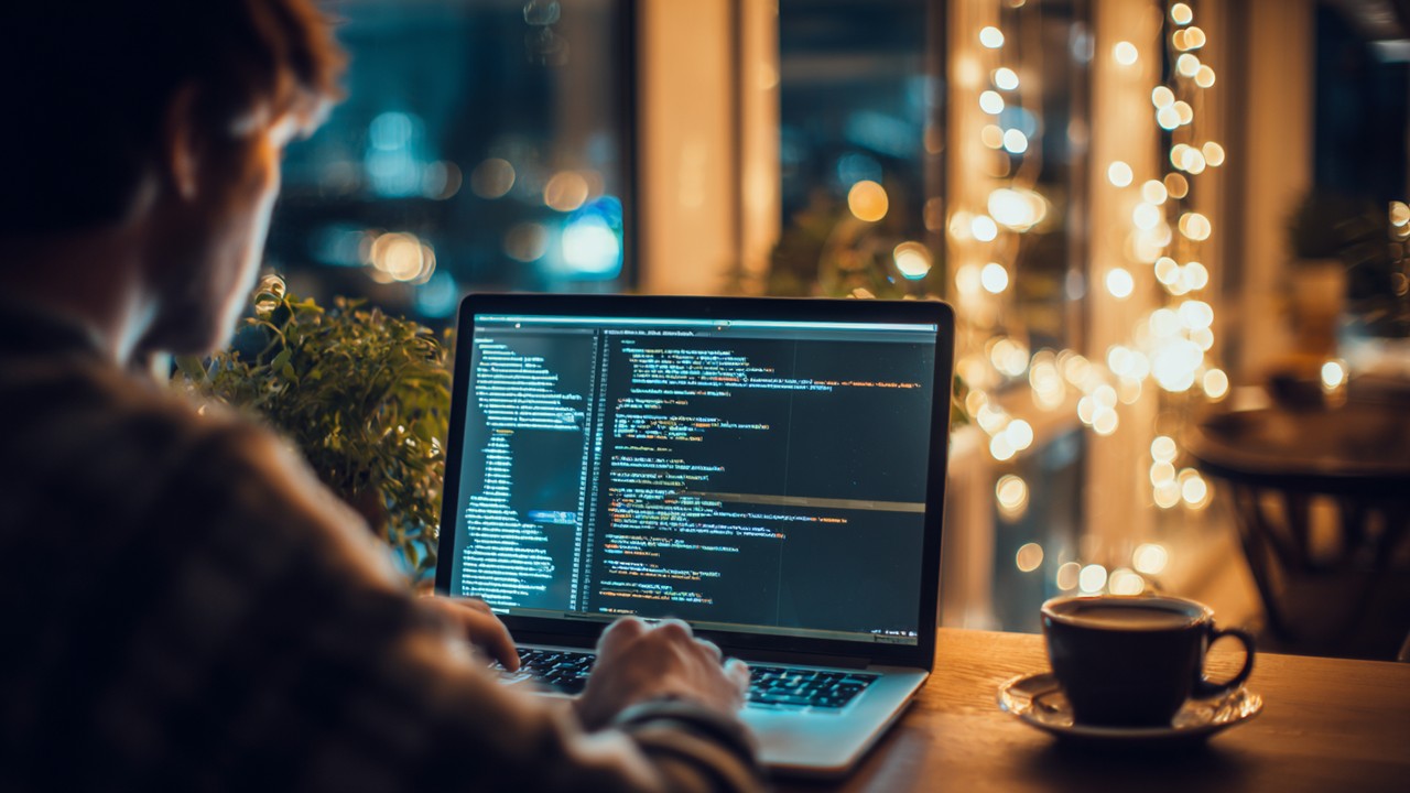 コード最適化に取り組むウェブ開発者の作業風景、コーヒーとともにパフォーマンスチューニングを行う画像