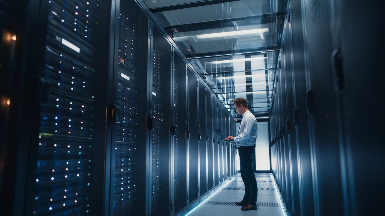 Modern data center server room with sleek racks, LED lights, and IT professional adjusting network equipment, highlighting efficient web server management.