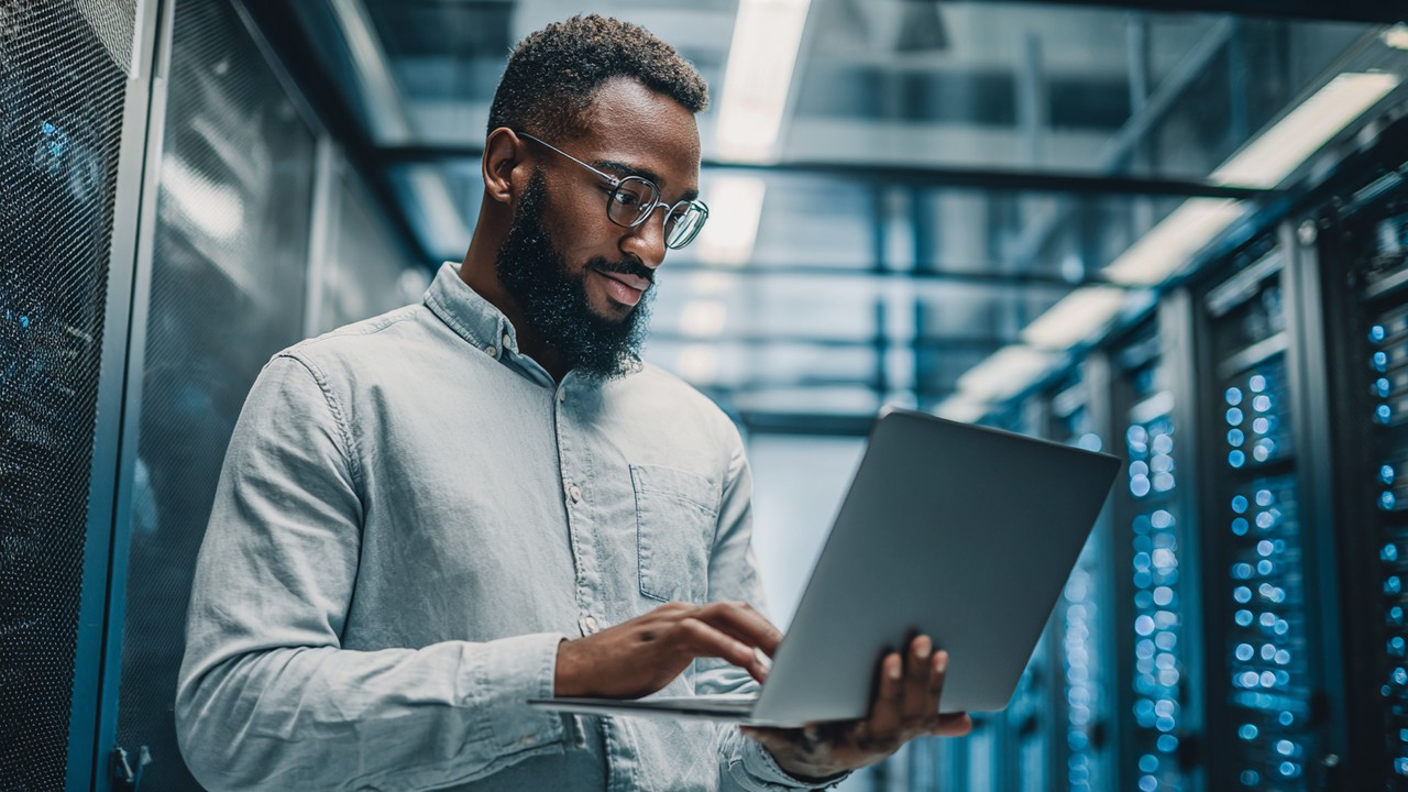 System administrator configuring a server on a laptop in a modern data center, focused on server setup and performance optimization.